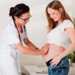 Médico palpando el vientre de una mujer embarazada