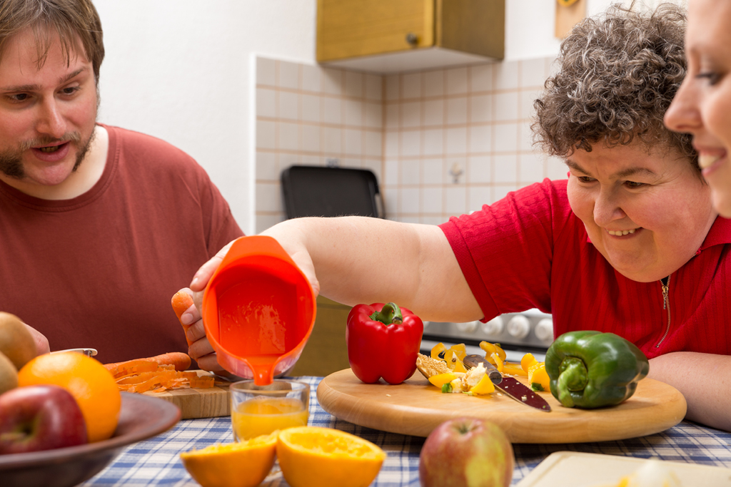 Mujer con discapacidad preparando un desayuno con zumo Mujer con discapacidad preparando un desayuno con zumo en un centro