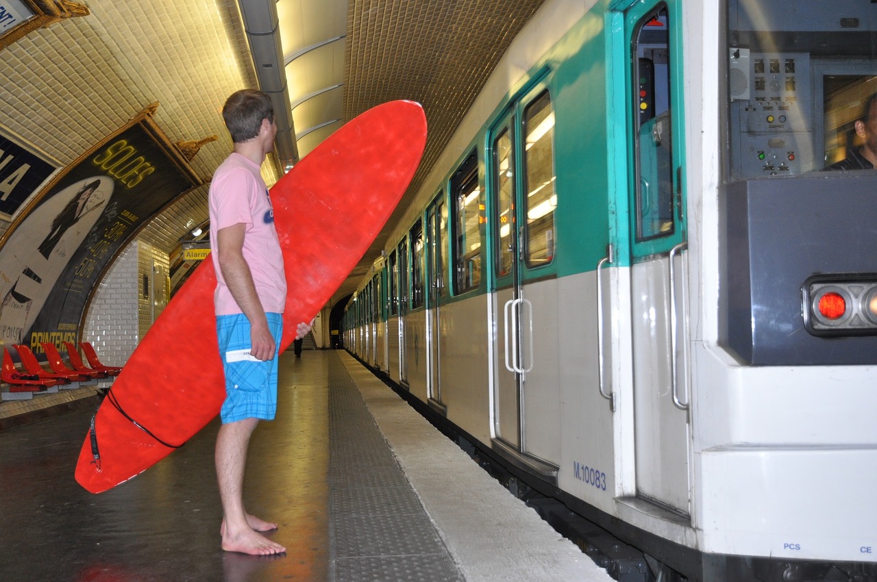 Campamentos de verano Chico con una tabla de surf roja en el metro
