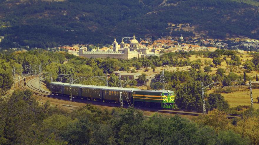 Tren de Felipe II viajando por la vía con San Lorenzo de El Escorial al fondo