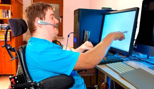 Hombre joven con parálisis cerebral trabajando en un ordenador Hombre joven con parálisis cerebral trabajando en un ordenador