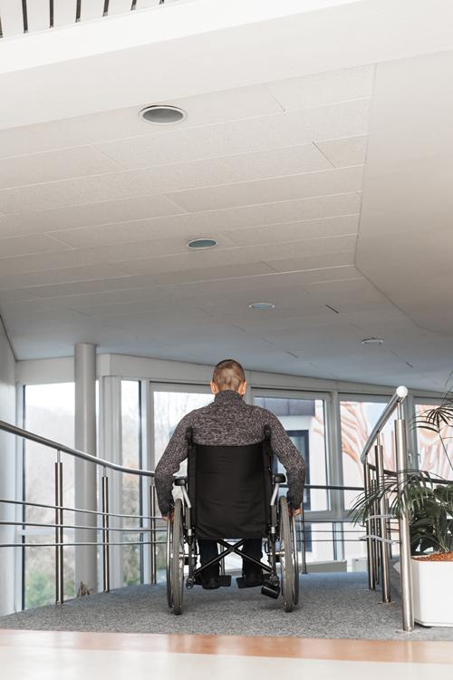 Acceso a la red de atención a personas con discapacidad Persona usuaria de silla de ruedas accediendo a un edificio