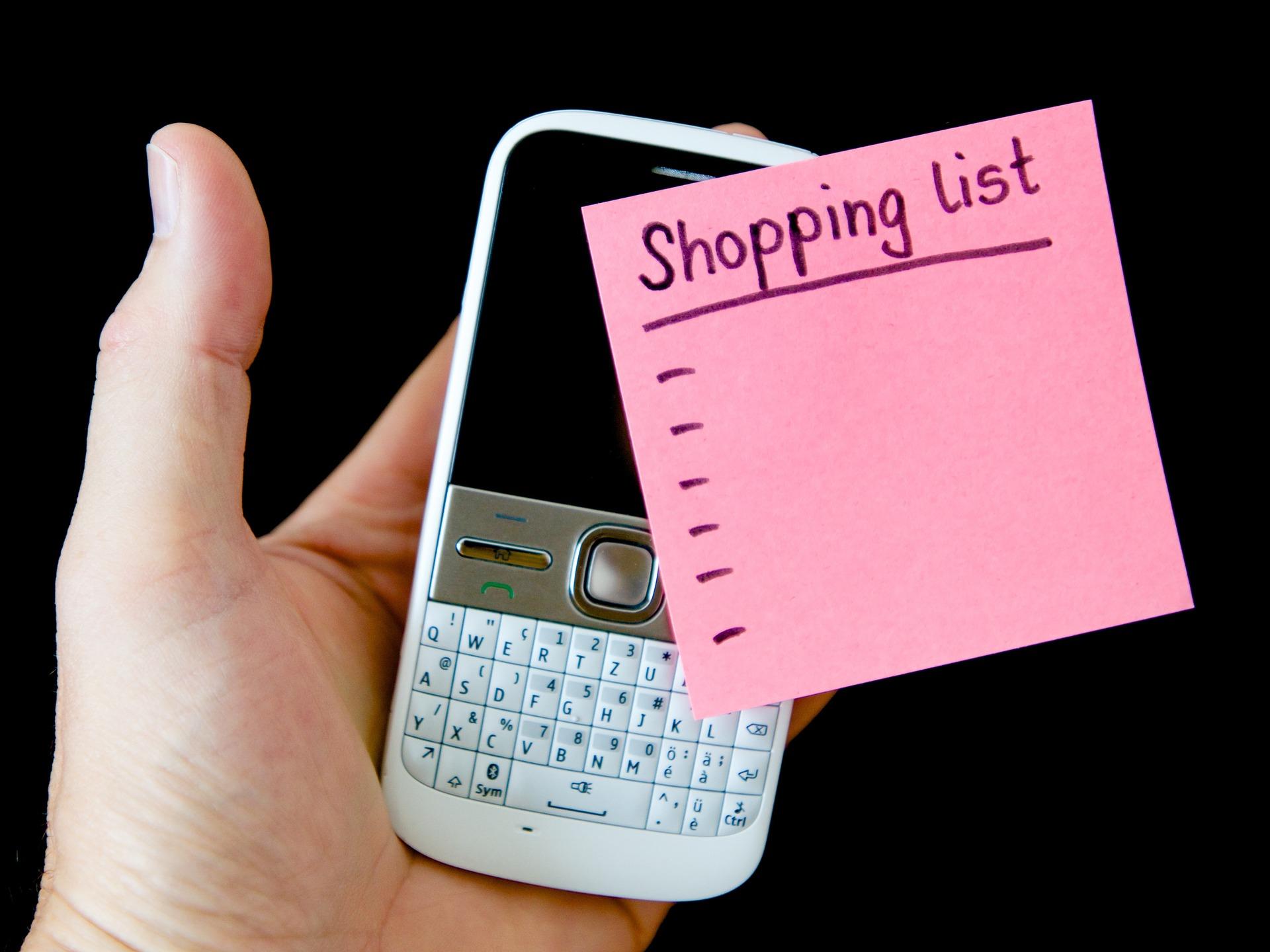 Consejos para hacer la compra Mano sujetando un móvil con un post-it con la lista de la compra