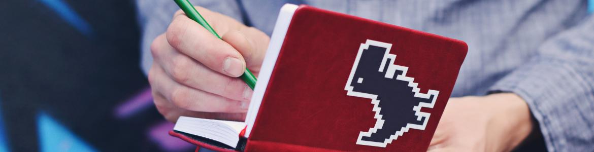 Asóciate Apuntando en una libreta roja con un dinosaurio en la portada