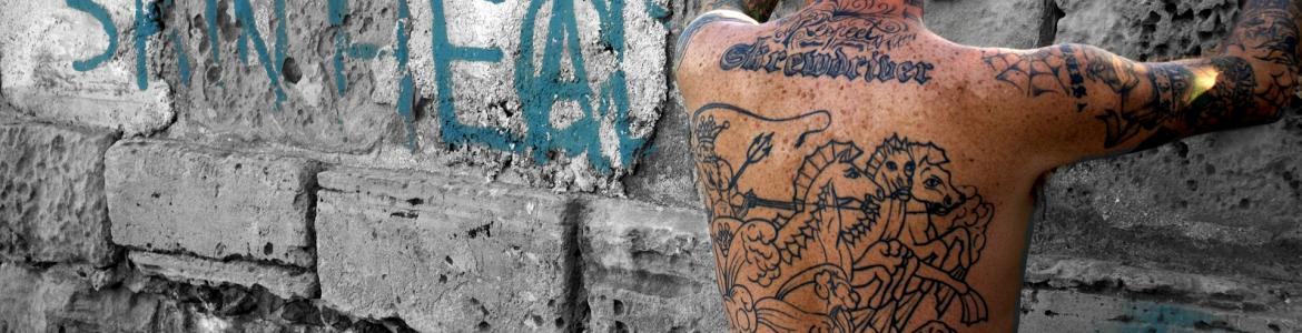Registros de adorno corporal Imagen de una persona de espaldas con un tatuaje, apoyo en una pared con un grafiti