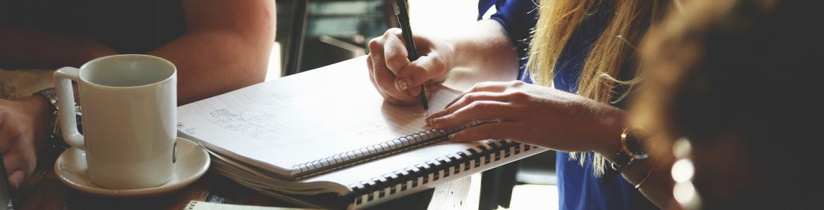 GUÍA PARA EXPERTOS EN EVALUACIÓN DE CALIDAD- ERASMUS+ Grupo de personas trabajando con una libreta, un portátil y un café