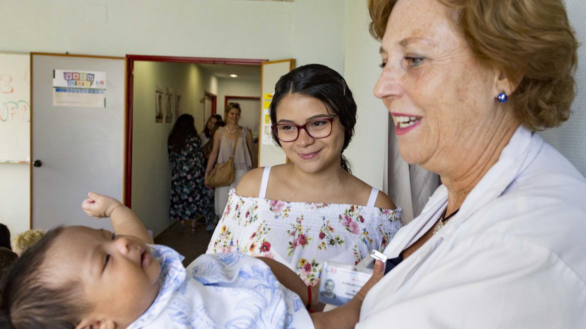 Matrona, madre y bebé Una matrona sostiene un bebé mientras su madre mira sonriente