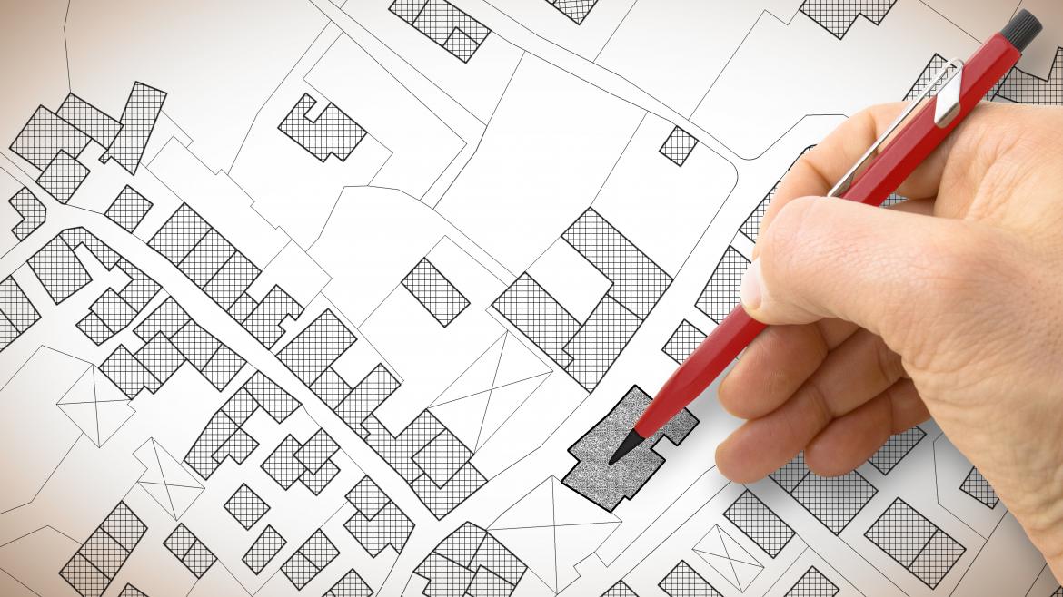 Mano con un lápiz dibujando un plano urbano