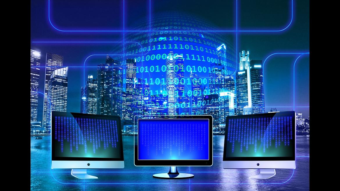 Ayuda Industria 4.0 Imagen con tres ordenadores en primer plano y fondo azul con dígitos binarios