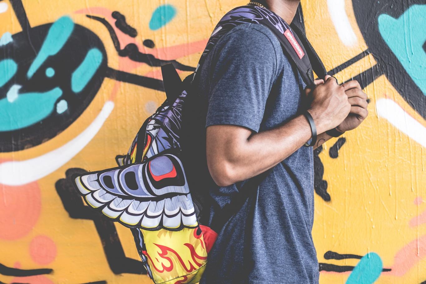 Curso de monitor Chico con mochila a la espalda pasando por una pared con graffiti