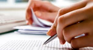 Mano con bolígrafo escribiendo en un folio