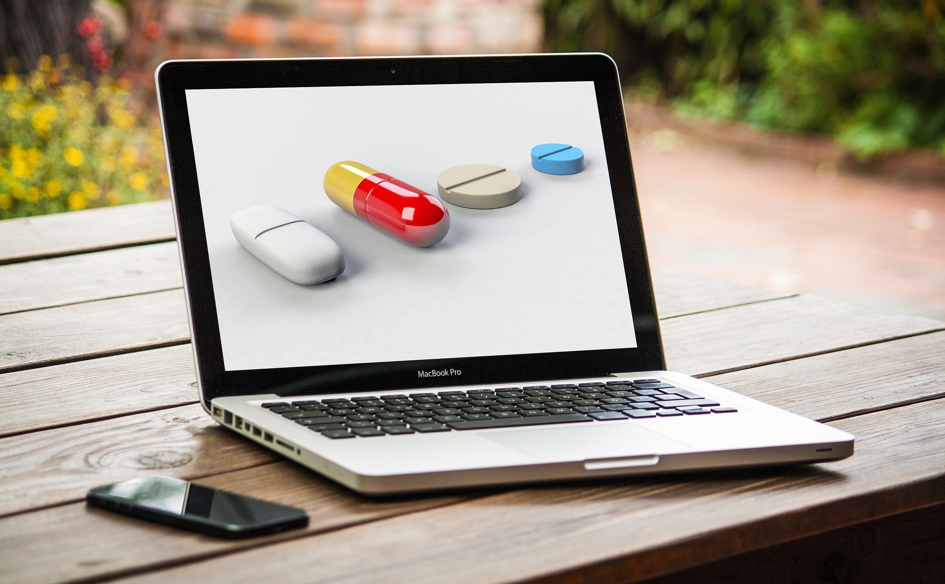 ordenador portátil abierto y con pastillas de medicamentos en la pantalla