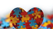 Corazón hecho con piezas de puzzle de colores amarillo , rojo y azul
