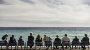 Fila de personas sentadas en sillas de espaldas mirando al mar