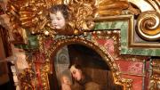 imagen de un fragmento de retablo con una cabeza de ángel esculpida y una pintura insertada en marco decorado