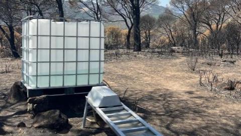 Bidón de agua para fauna silvestre en terreno afectado por el incendio de la sierra oeste