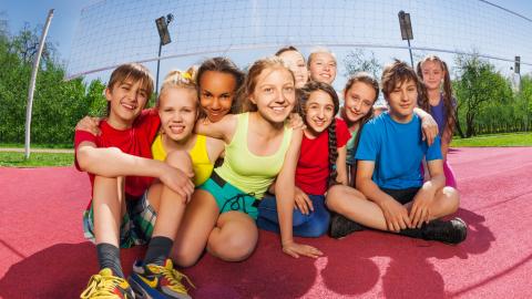 Niños sonrientes sentados en una cancha de voleibol