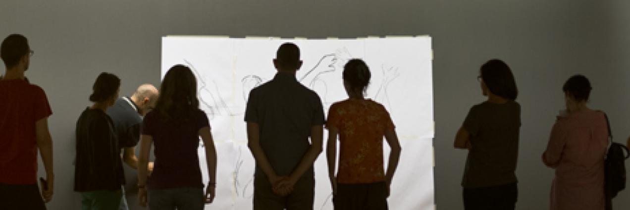 Grupo de gente joven observando un lienzo en blanco en una sala de exposiciones