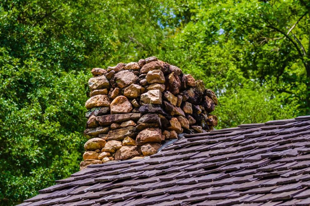 Casa con chimenea Chimenea de piedra en lo alto de un tejado de pizarra
