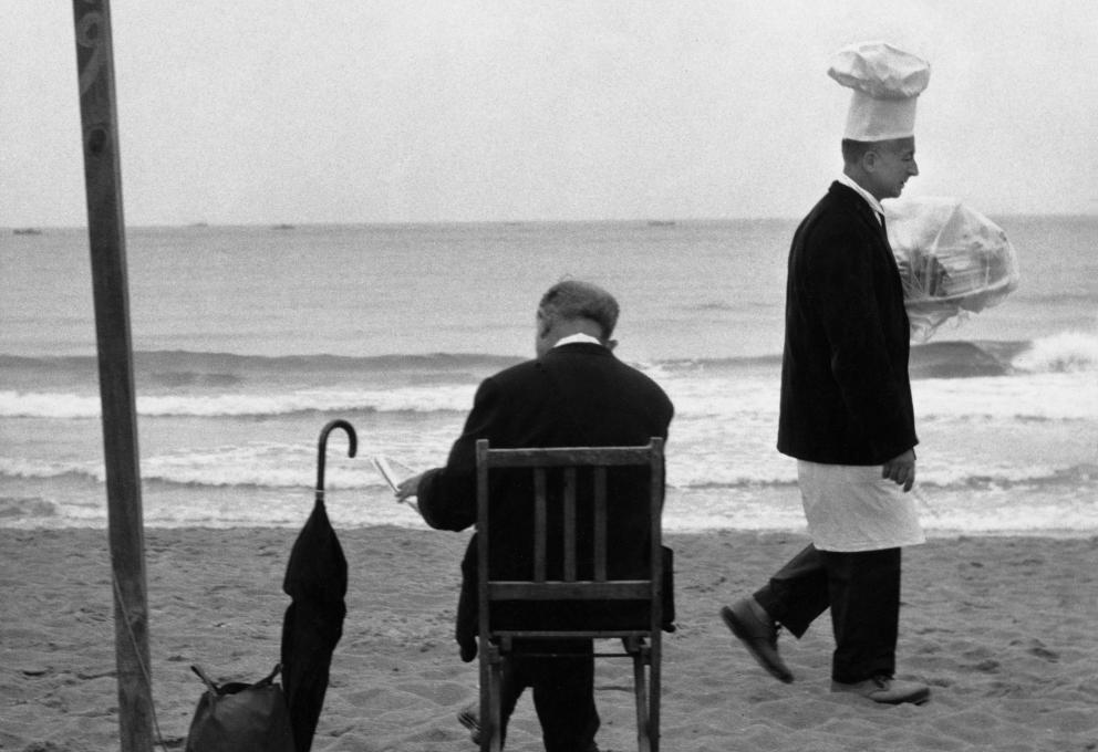 Hombre leyendo en la plaza y cocinero con bandeja