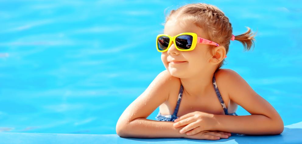 Niña sonriente apoyada en el borde de la piscina