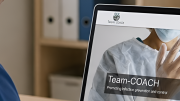 Detalle de profesional con pijama azul mirando pantalla ordenador donde está portada TEAM COACH