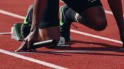 Atleta en posición de salida sujetando testigo de relevos