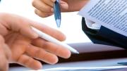 Imagen en primer plano de las manos de dos personas con documentos sobre una mesa