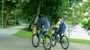 Dos chicas en bici por zona ajardinada