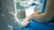 Profesional sanitario consuela con su mano puesta en el brazo del paciente