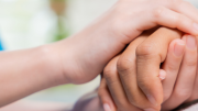 Una mano de sanitaria sobre la mano de un paciente