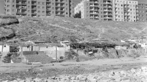 imagen de un descampado con chabolas y edificios al fondo