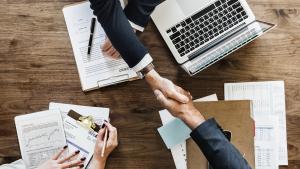 Brazos de personas en una escena en la que firma un contrato de trabajo