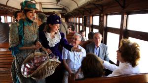 Pasajeros del Tren de la Fresa reciben una caja de fresas de dos mujeres vestidas de época