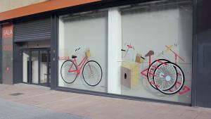 Fachada de la Sala de Arte Joven con vinilos que representan bicicletas de colores