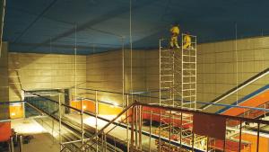 Obras en la estación Congosto Obreros subidos a un andamio pintando el techo de azul de la estación Congosto