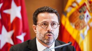 Primer plano del consejero con la bandera de España y la de la Comunidad de Madrid de fondo