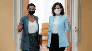 La presidenta posando y saludando a la prensa junto a Rocío Monasterio en la puerta de la sala de la reunión