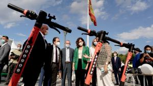 La presidenta acompañada por otros asistentes mirando unos patinetes eléctricos