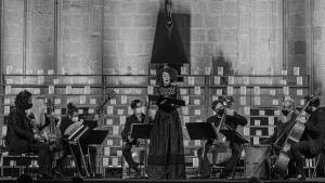 Una mujer canta en un escenario acompañado de varios músicos