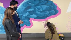 El viceconsejero de Transportes, Carlos Díaz-Pache, inaugura el mural con motivo de la celebración del 8 de marzo El consejero observa como la artista pinta el mural