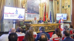 Vista del estrado de la sala plenaria con autoridades de la Clausura, pantallas, banderas y trasera conmemorativa con Puerta del Sol