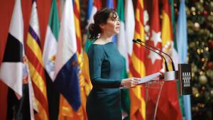 Díaz Ayuso reivindica una “España fiel” con voluntad “firme y profunda” de convivir “en democracia y libertad” La presidenta con un vestido verde delante de las banderas en el acto