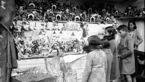 Foto en blanco y negro de niños mirando un puesto con figuritas del Belén