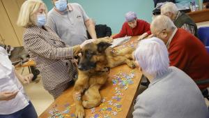 La consejera junto a personas mayores acariciando un perro