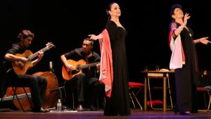 imagen de dos mujeres cantando e interpretando y detrás de ellas, sentados, dos guitarristas