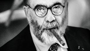 Hombre barbudo y con gafas fumando un puro