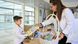 Un profesional sanitario presta un libro a un niño hospitalizado