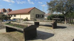 Huerto didáctico en el Centro de educación ambiental Bosque Sur Mesas de cultivo en primer plano y edificio del centro al fondo
