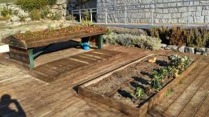 Mesas de trabajo en el huerto del Centro de educación ambiental El Águila Mesa alta de cultivo y bancal, ambos de madera con plantaciones y suelo de también de madera